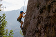 © zhukovvvlad - A determined and strong boy climber climbs a steep mountain wall. Extreme sports and rock climbing.