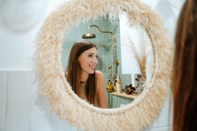 Smiling Woman Looking At Herself In Bathroom Mirror