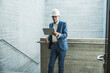 © Westend61 - Senior engineer wearing hardhat and using tablet PC near wall