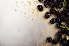  A Bunch Of Blackberries On A White Surface With Some Gold Flakes On The Top Of The Image And Some Green Leaves On The Bottom Of The Image.