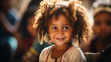 Fototapeta Uliczki - A portrait of a curly-haired young child smiling warmly, with a backdrop of soft-focused children, emphasizing diversity and joy.