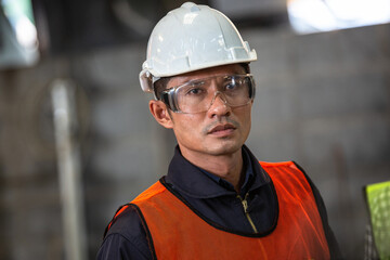 Wall Mural - Asian man engineer industrial foreman wearing protective eyewear standing with arms crossed. technician worker in safety uniform. Industry technology manufacturing factory. looking with vision.