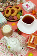 Tea party on a pink background. Poster for interior. A cup of tea, a teapot, desserts and a candle on a bright background create a cozy atmosphere.