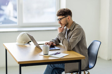 Wall Mural - Creative business man working on a laptop in an open plan office.