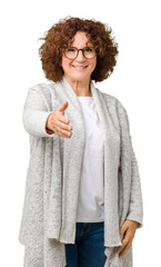 Poster - Beautiful middle ager senior woman wearing jacket and glasses over isolated background smiling friendly offering handshake as greeting and welcoming. Successful business.