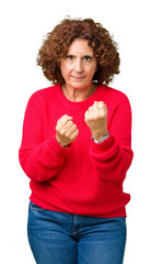 Poster - Beautiful middle ager senior woman red winter sweater over isolated background Ready to fight with fist defense gesture, angry and upset face, afraid of problem