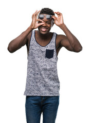 Wall Mural - Young african american man with happy face smiling doing ok sign with hand on eye looking through fingers