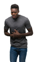 Poster - Young african american man wearing grey t-shirt with hand on stomach because indigestion, painful illness feeling unwell. Ache concept.