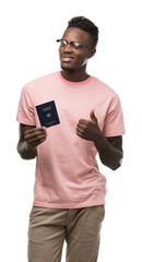 Canvas Print - Young african american man holding german passport happy with big smile doing ok sign, thumb up with fingers, excellent sign