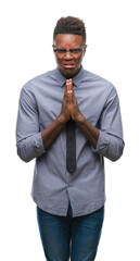 Canvas Print - Young african american business man over isolated background begging and praying with hands together with hope expression on face very emotional and worried. Asking for forgiveness. Religion concept.