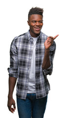 Canvas Print - Young african american man over isolated background with a big smile on face, pointing with hand and finger to the side looking at the camera.