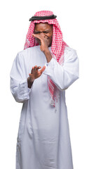 Wall Mural - Young arabic african man wearing traditional keffiyeh over isolated background smelling something stinky and disgusting, intolerable smell, holding breath with fingers on nose. Bad smells concept.