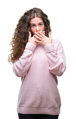 Poster - Beautiful brunette curly hair young girl wearing pink winter sweater over isolated background shocked covering mouth with hands for mistake. Secret concept.