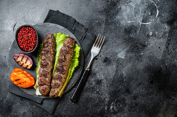 Wall Mural - Grilled Urfa kebab with tomato, salad and onion. Black background. Top view. Copy space