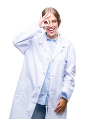 Poster - Beautiful young blonde doctor woman wearing white coat over isolated background doing ok gesture with hand smiling, eye looking through fingers with happy face.