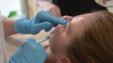Cropped unrecognizable medical staff performing a facial filler injection on a woman to reduce the appearance of dark circles