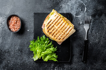 Wall Mural - Club sandwich panini with ham, tomato, cheese and basil. Black background. top view