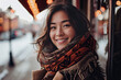 © ADDICTIVE STOCK - Generative AI image of a young Asian woman smiling warmly, wearing a stylish scarf and looking away from the camera on a blurry city background during the evening