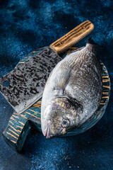 Wall Mural - Sea bream or dorado fish on fish market cutting board. Blue background. Top view