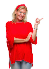 Sticker - Middle age blonde woman over isolated background with a big smile on face, pointing with hand and finger to the side looking at the camera.