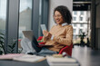 © Yaroslav Astakhov - Smiling business woman is using phone sitting in office during break time with laptop