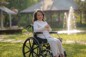 Wall Mural - Happy old woman sitting in a wheelchair in park, healthy strong medical concept.