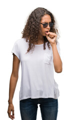 Poster - Young hispanic woman wearing sunglasses feeling unwell and coughing as symptom for cold or bronchitis. Healthcare concept.