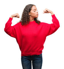 Wall Mural - Young hispanic woman wearing red sweater showing arms muscles smiling proud. Fitness concept.