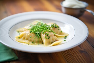 Wall Mural - plate of boiled polish pierogi with sour cream and chives