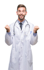 Sticker - Young handsome doctor man over isolated background celebrating surprised and amazed for success with arms raised and open eyes. Winner concept.