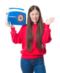 Wall Mural - Young Chinese woman over isolated background holding vintage radio very happy and excited, winner expression celebrating victory screaming with big smile and raised hands