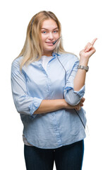 Wall Mural - Young caucasian business woman wearing call center headset over isolated background with a big smile on face, pointing with hand and finger to the side looking at the camera.