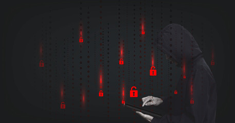 Fototapete - Cybercrime concept. The man in a hood is standing and hacking with the iPad in the dark room.  