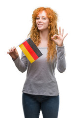 Sticker - Young redhead woman holding flag of Germany doing ok sign with fingers, excellent symbol