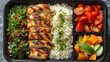 food in a black divided catering plastic box, black clean background, top view, chicken with rice and salad