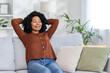 © Tetiana - Relaxed african american woman enjoying a peaceful moment on a cozy couch at home with eyes closed
