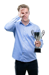 Canvas Print - Young handsome blond man holding a trophy with happy face smiling doing ok sign with hand on eye looking through fingers