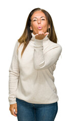 Sticker - Beautiful middle age adult woman wearing winter sweater over isolated background looking at the camera blowing a kiss with hand on air being lovely and sexy. Love expression.