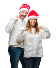 Wall Mural - Middle age hispanic couple wearing christmas hat over isolated background looking confident with smile on face, pointing oneself with fingers proud and happy.