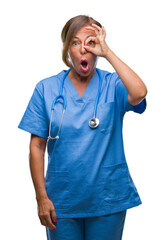 Poster - Middle age senior nurse doctor woman over isolated background doing ok gesture shocked with surprised face, eye looking through fingers. Unbelieving expression.