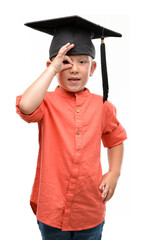 Poster - Dark haired little child wearing graduation cap with happy face smiling doing ok sign with hand on eye looking through fingers