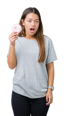 Sticker - Young beautiful woman eating pink donut over isolated background scared in shock with a surprise face, afraid and excited with fear expression