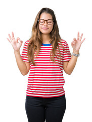 Sticker - Young beautiful brunette woman wearing glasses and stripes t-shirt over isolated background relax and smiling with eyes closed doing meditation gesture with fingers. Yoga concept.