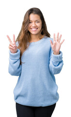 Canvas Print - Young beautiful brunette woman wearing blue winter sweater over isolated background showing and pointing up with fingers number seven while smiling confident and happy.