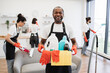 © sofiko14 - Portrait of young African American man professional cleaning worker holding a bucket for washing with detergents on bright kitchen studio background, copy space.