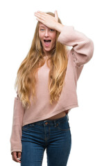 Sticker - Blonde teenager woman wearing pink sweater surprised with hand on head for mistake, remember error. Forgot, bad memory concept.