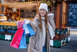 © Iryna - smiling young woman with colorful shopping gift bags  having a fun time,  using phones,   outdoor in an urban winter city. people, communication,  shopping and lifestyle concept