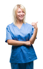 Poster - Young beautiful blonde nurse doctor woman over isolated background smiling with happy face looking and pointing to the side with thumb up.