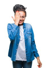 Wall Mural - Young braided hair african american girl wearing glasses over isolated background covering one eye with hand with confident smile on face and surprise emotion.