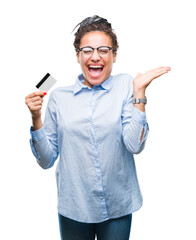 Poster - Young african american girl holding credit card over isolated background very happy and excited, winner expression celebrating victory screaming with big smile and raised hands